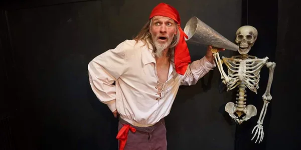 Conteur déguisé en pirate avec un squelette lors d'un spectacle de contes imaginaires pour enfants.