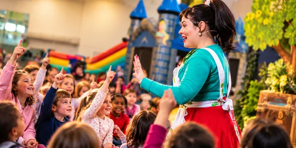 Conteuse professionnelle faisant participer des enfants à un spectacle de contes interactifs lors d'un événement d'entreprise.