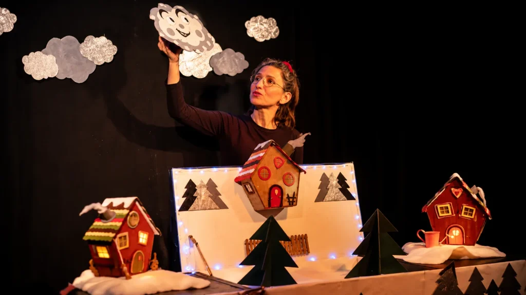 Spectacle pour enfants Flocons parle avec une artiste dans un décor de village enneigé